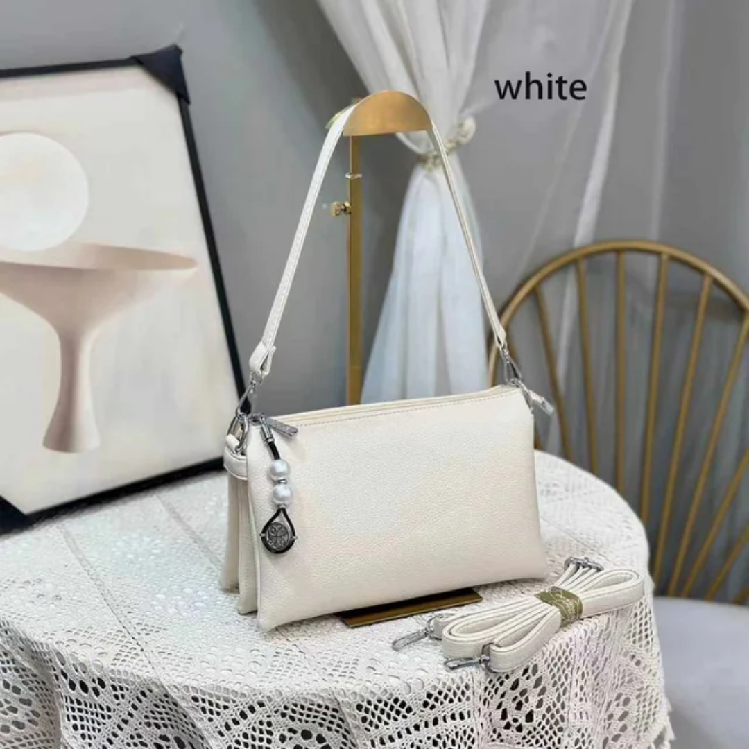 Faux leather crossbody bag with a pearl pendant and chain shoulder strap. 