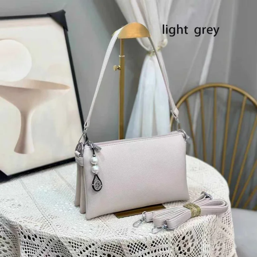 Faux leather crossbody bag with a pearl pendant and chain shoulder strap. 