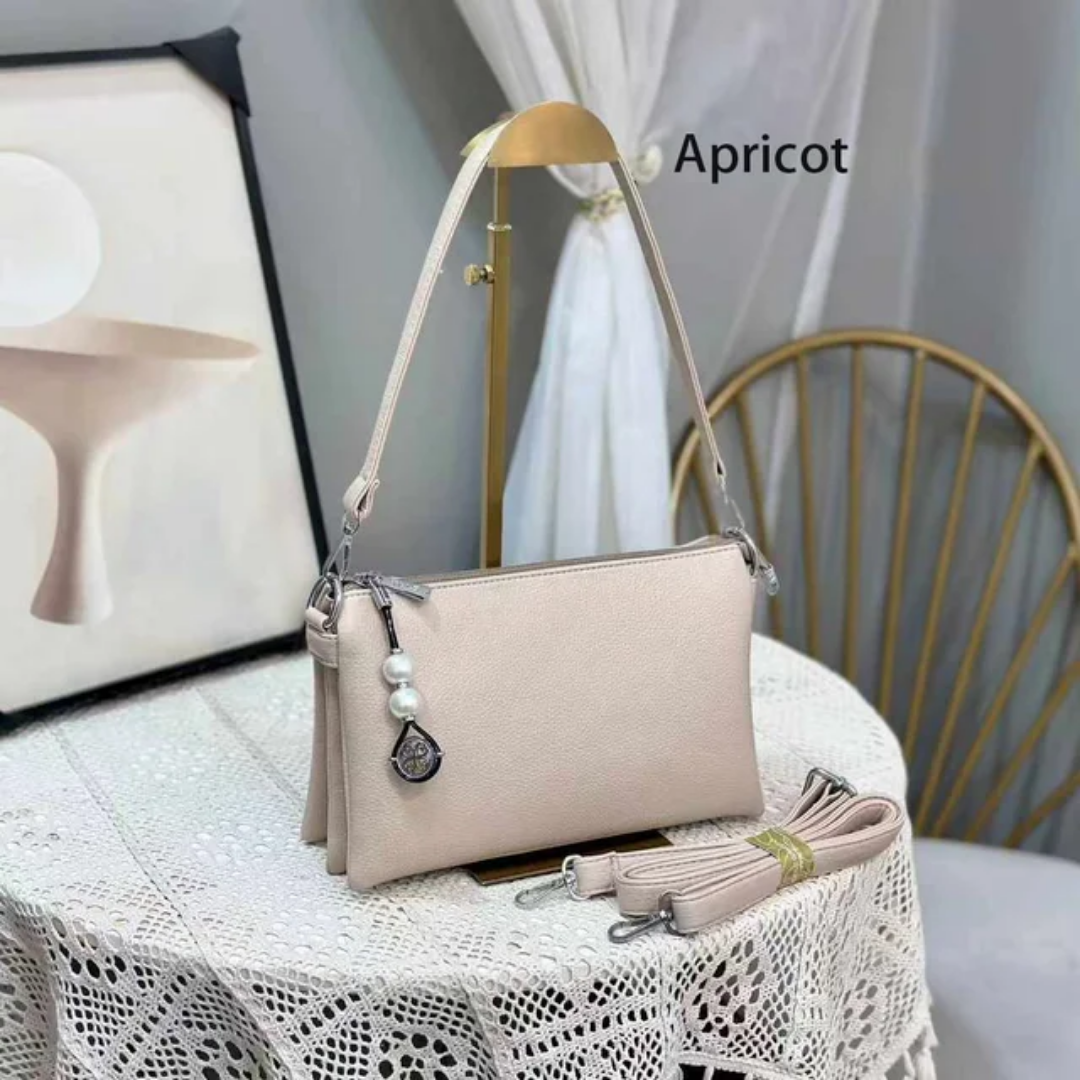 Faux leather crossbody bag with a pearl pendant and chain shoulder strap. 