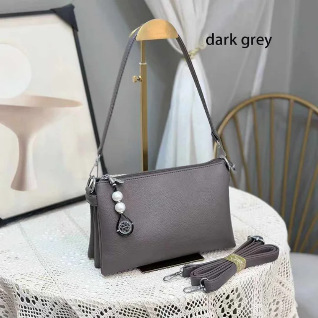 Faux leather crossbody bag with a pearl pendant and chain shoulder strap. 